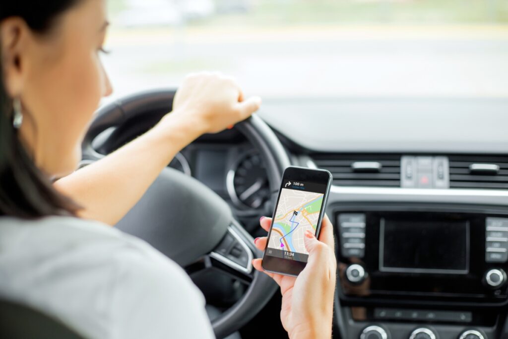 Woman navigating with smartphone GPS in a modern car, emphasizing technology and safe driving.