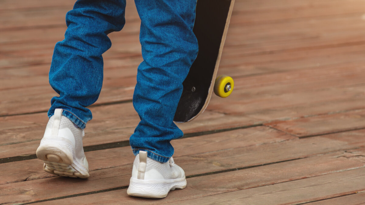 Close-up of a man wearing jeans with a skateboard