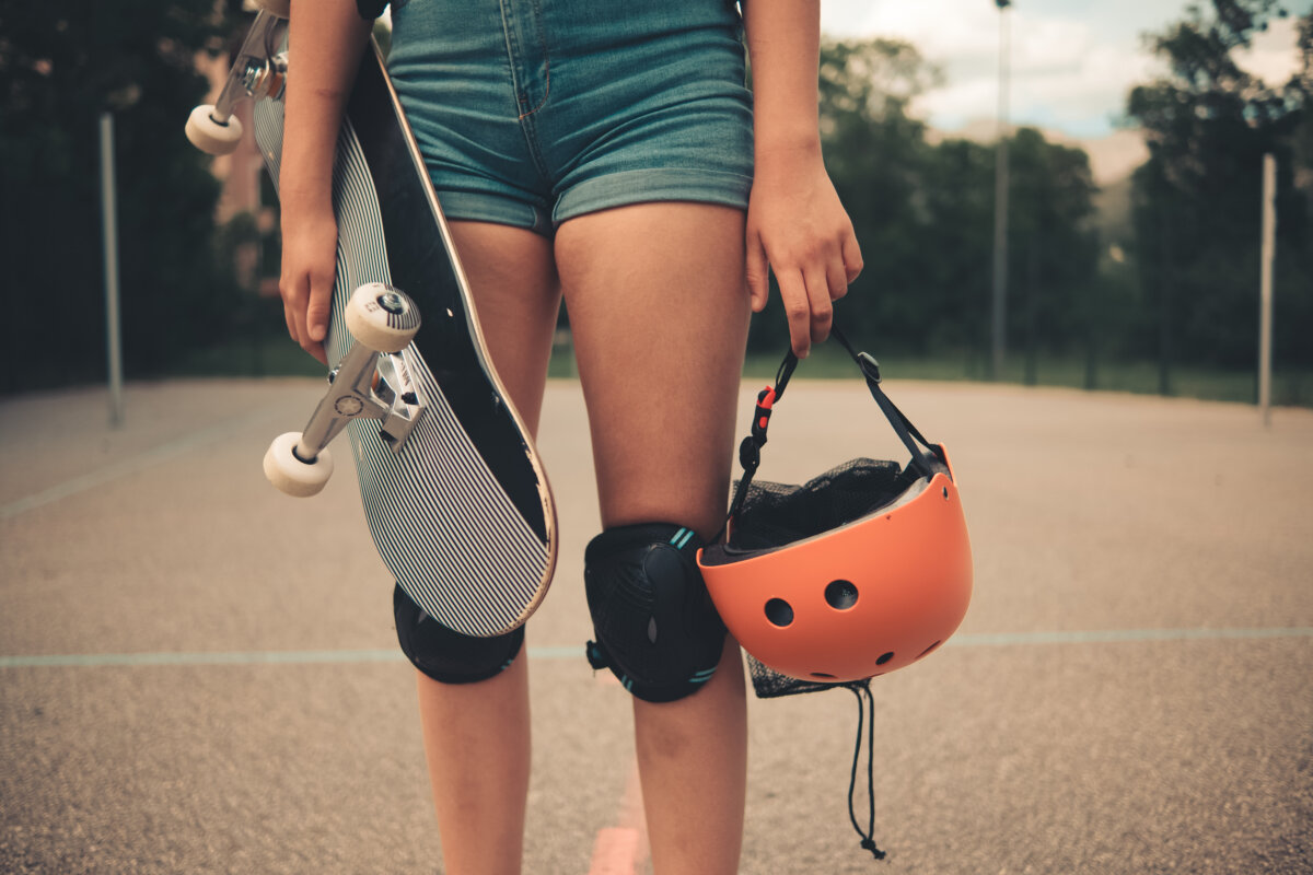 Woman with a skateboard, helmet and a knee pads for protection