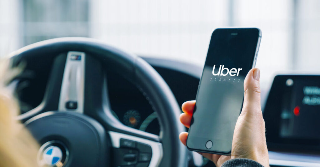Uber driver using smartphone app in a modern car, showcasing convenient ride-hailing technology.